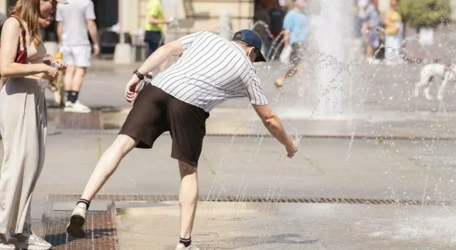 Caldo record con persone che si rinfrescano alle fontane pubbliche