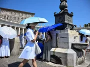 Caldo record in Europa, Oms: oltre 1.300 morti in una settimana. Allerta maltempo in 9 regioni Persone si proteggono dal caldo estremo in una piazza europea