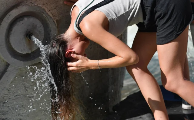 Una donna si rinfresca in una fontana mentre l'Italia affronta il picco dell'ondata di caldo.